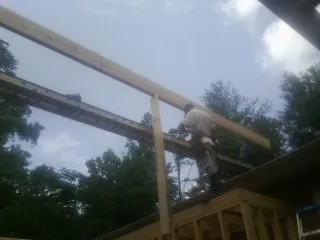 Carpenter setting a ridge beam over a new addition frame — Ice Dam Removal by Roofing Brothers in Wyola