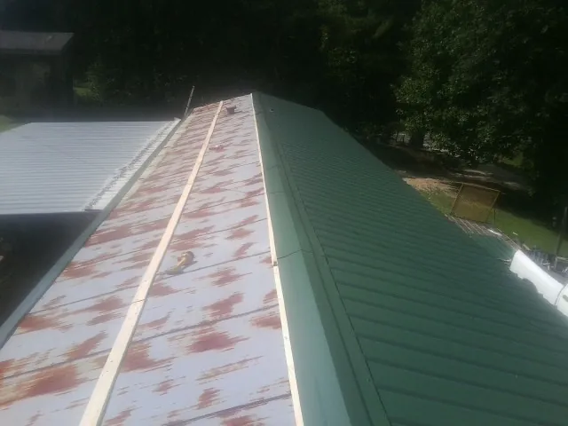 Old rusted panels beside newly installed green metal roofing — Wind Damage Roof Repair by Roofing Brothers in Wyola