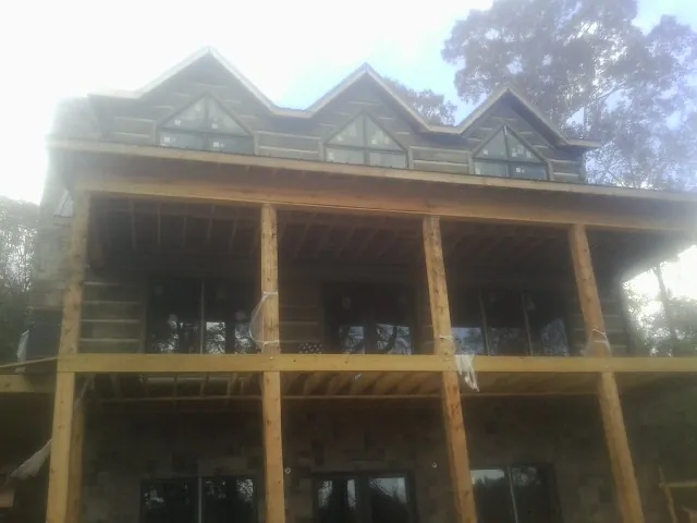 Dormers and porch framing on a large log home under construction — Roof Coating work by our crew in Wyola