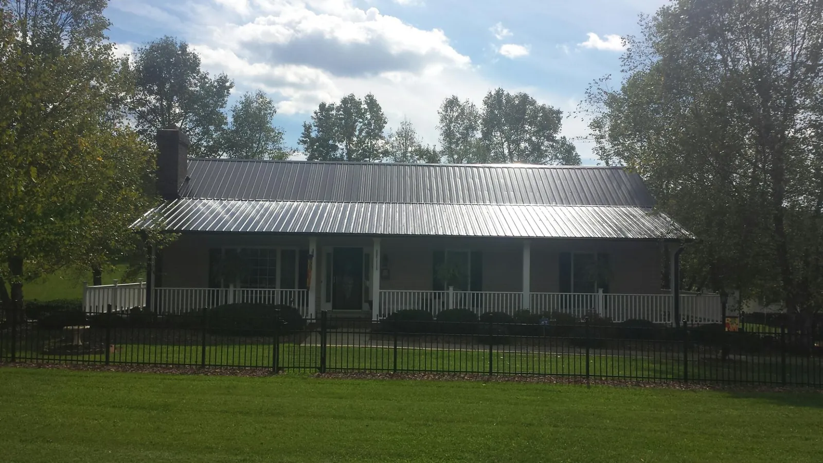 Gray metal roof on a brick ranch with a full width front porch — Gutter Guard Installation work by our crew in Wyola