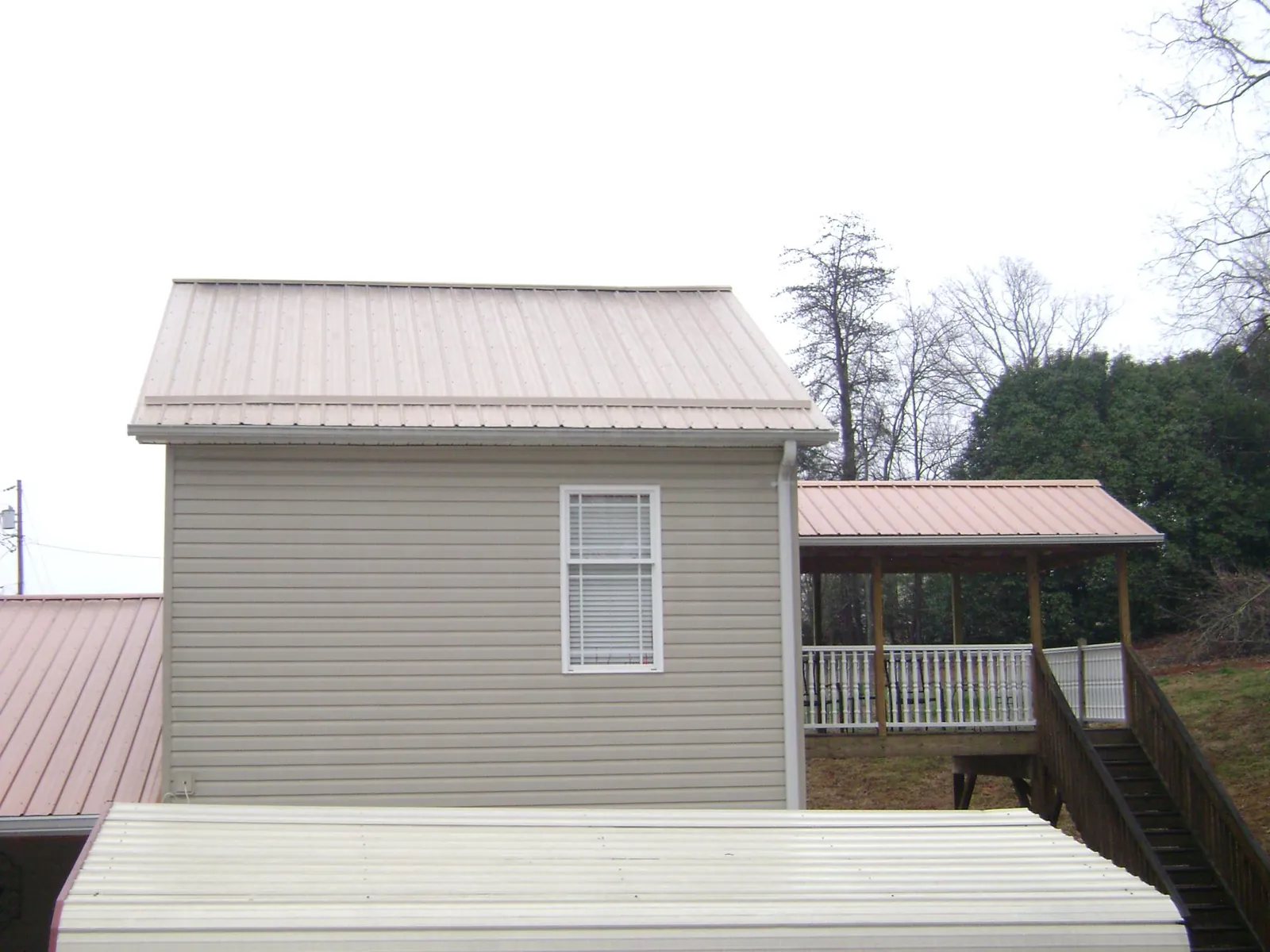 Tan metal roofs on a two story addition and attached porch, from a Roof Replacement job in Wyola