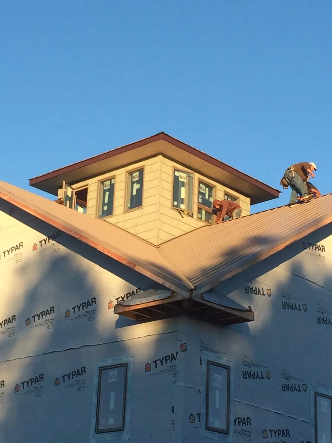 Roofers working around a rooftop cupola on a new metal roof at sunset — Roof Waterproofing in Wyola by Roofing Brothers